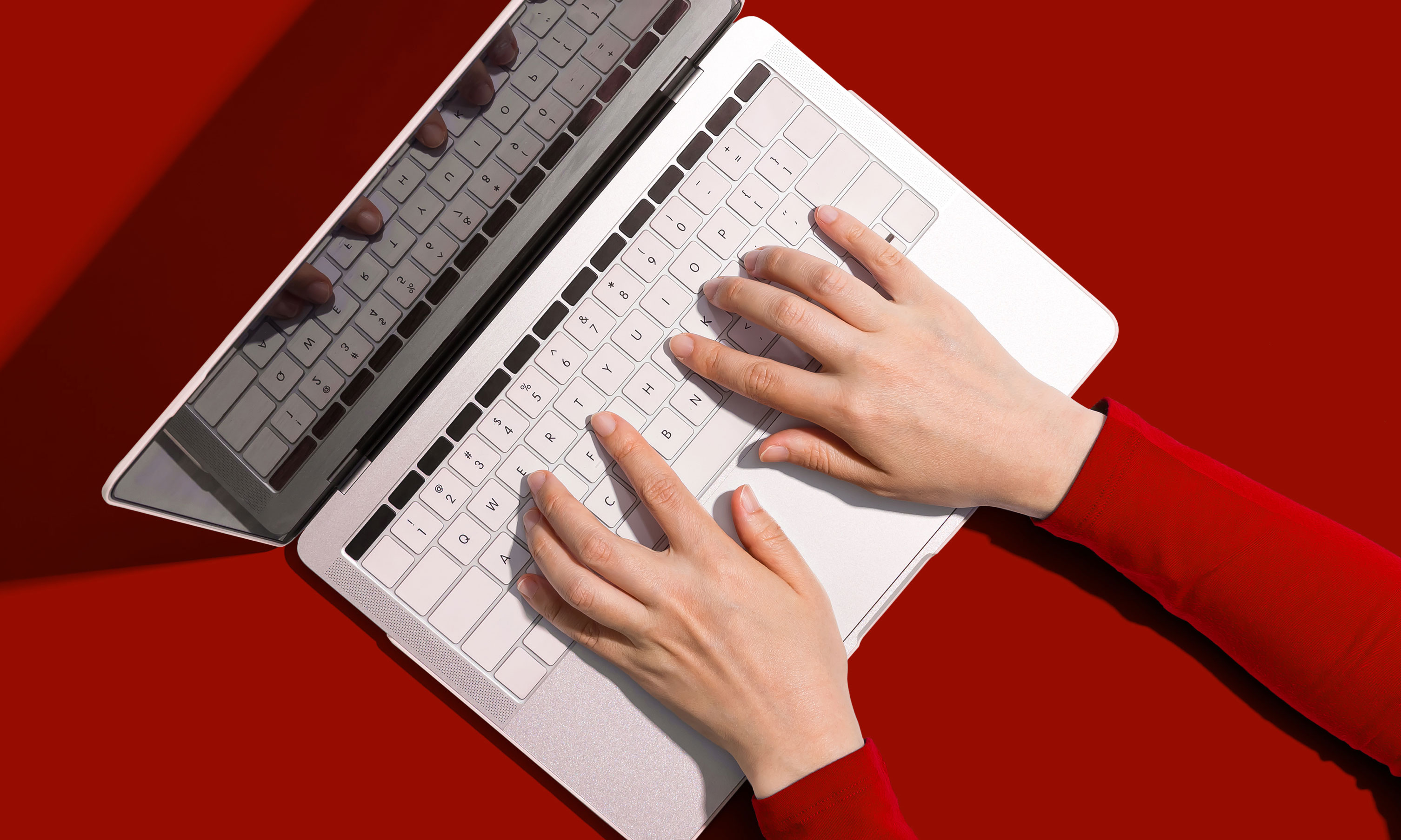 Top down view of hands typing on a laptop keyboard