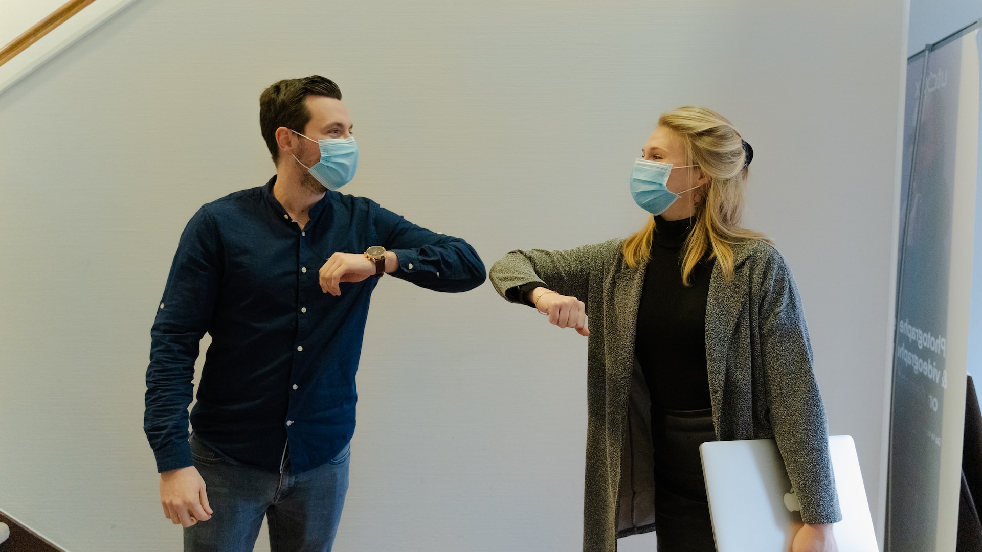 A man and a woman great each other during the covid pandemic by touching elbows